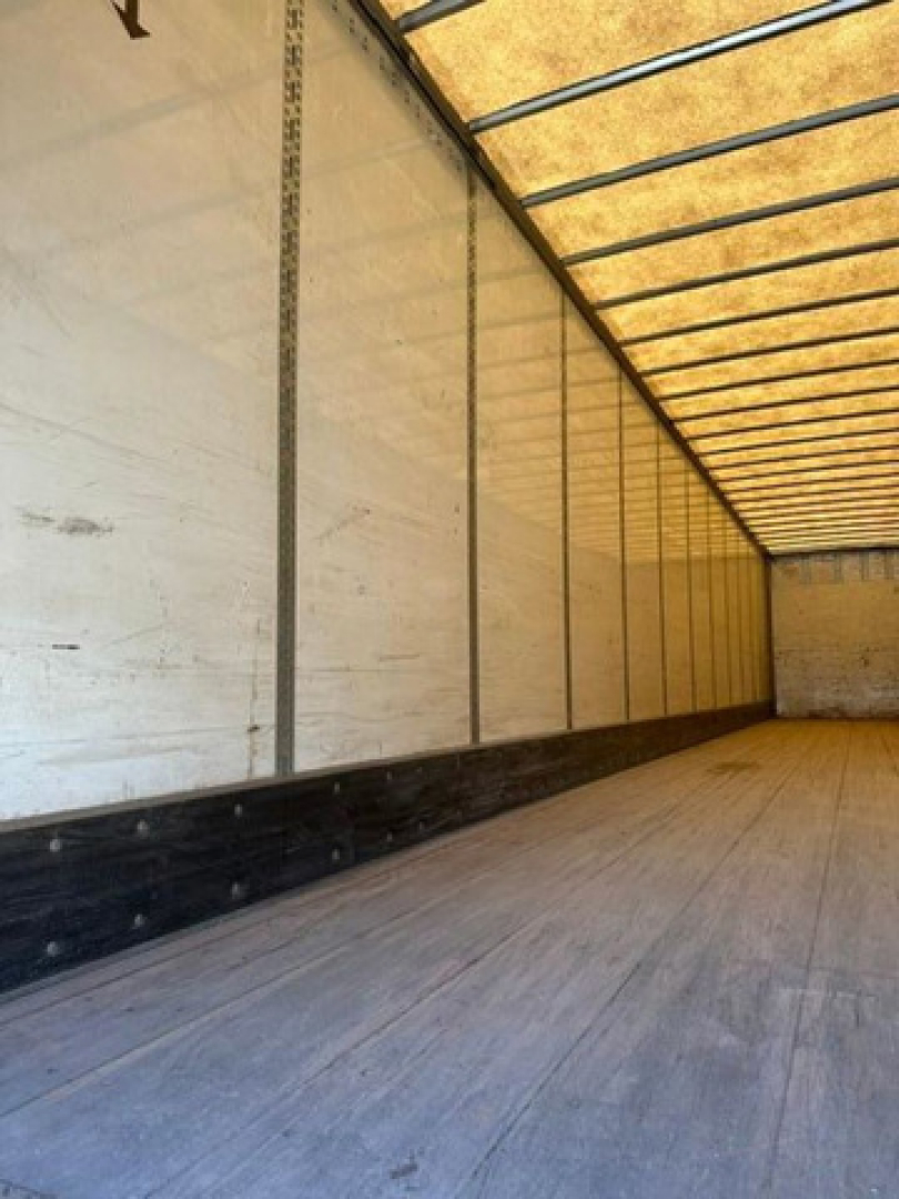 Trailer interior showing empty cargo area with wooden floor and side walls; no visible equipment labels or fluid reservoirs.