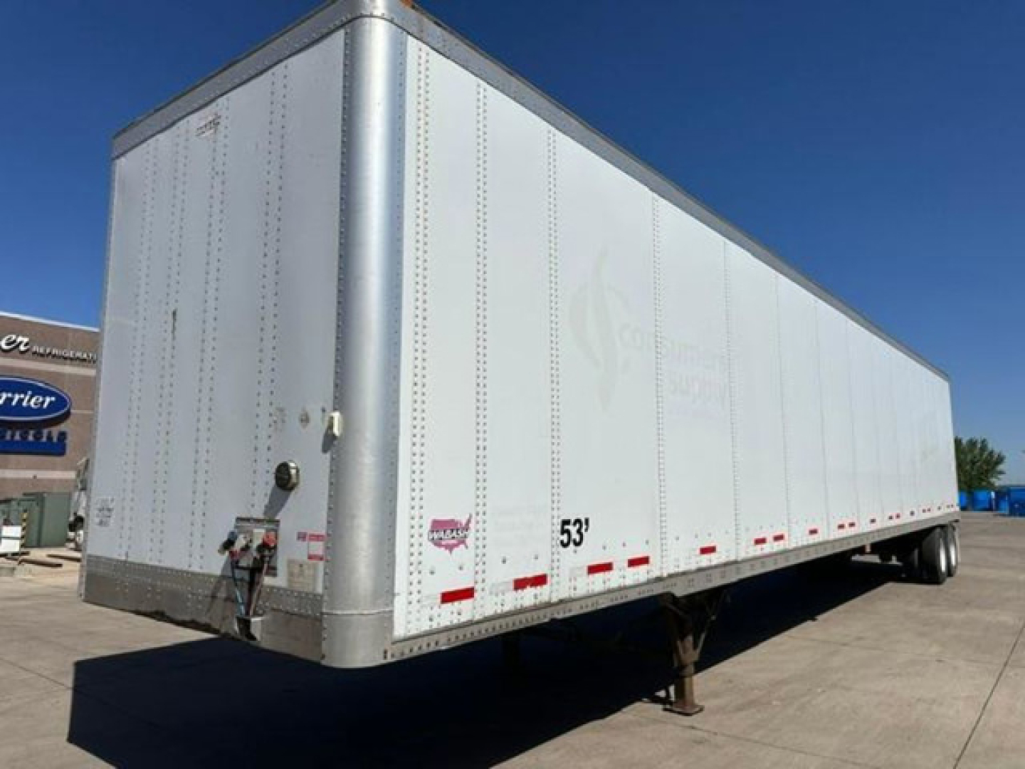 Trailer side view showing a white 53' Wabash van trailer with silver front corner posts and reflective striping.