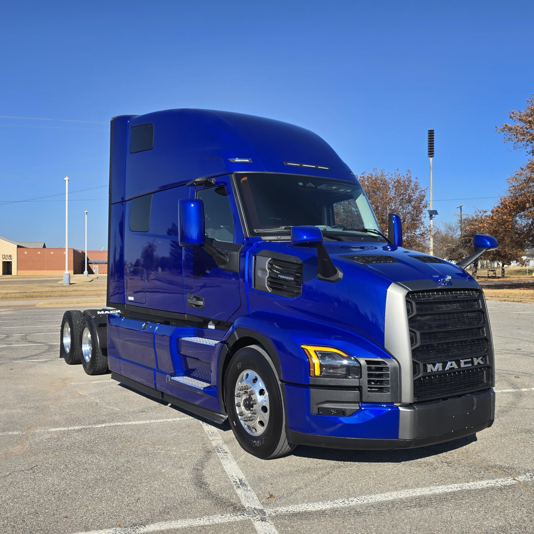 Blue 2026 Mack PR64T76H sleeper tractor truck in parking lot, side view showing large cab, dual rear axles, and Mack grille.