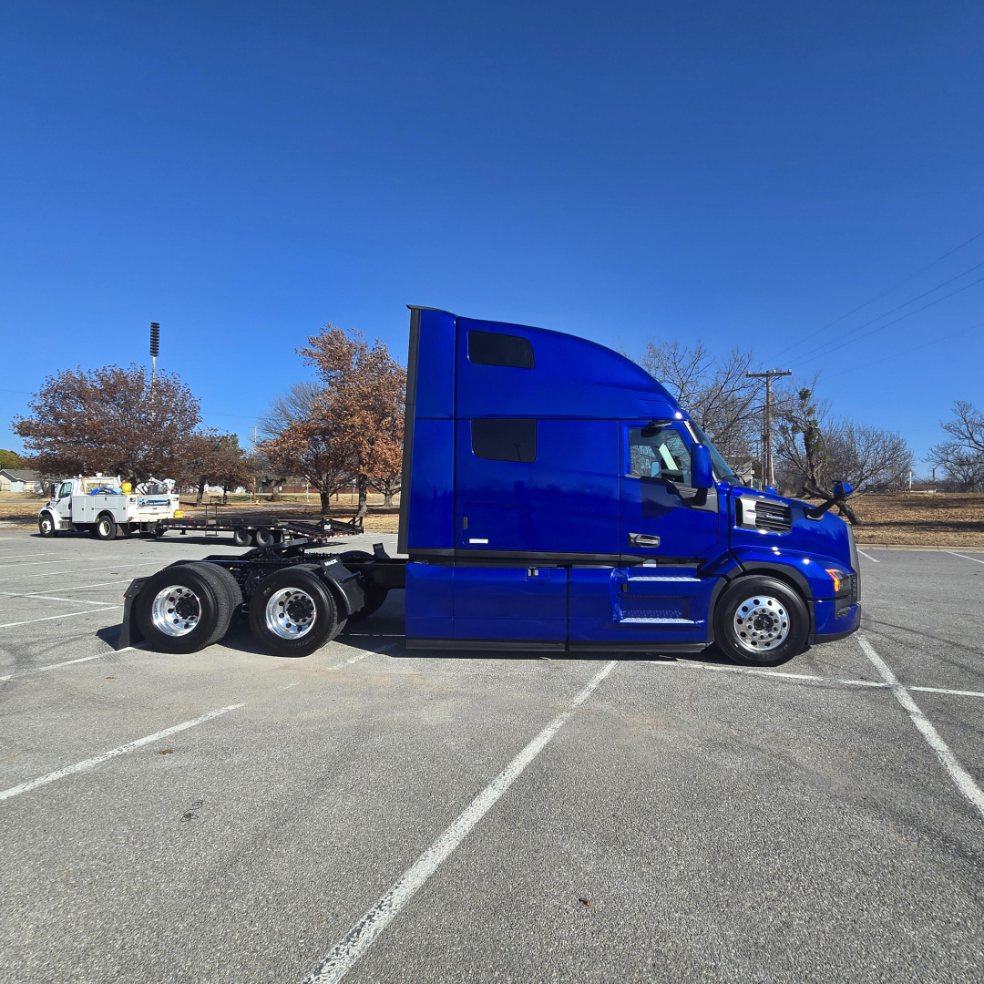 Blue Mack PR64T76H truck in a parking lot side view showing sleeper cab and rear axles.