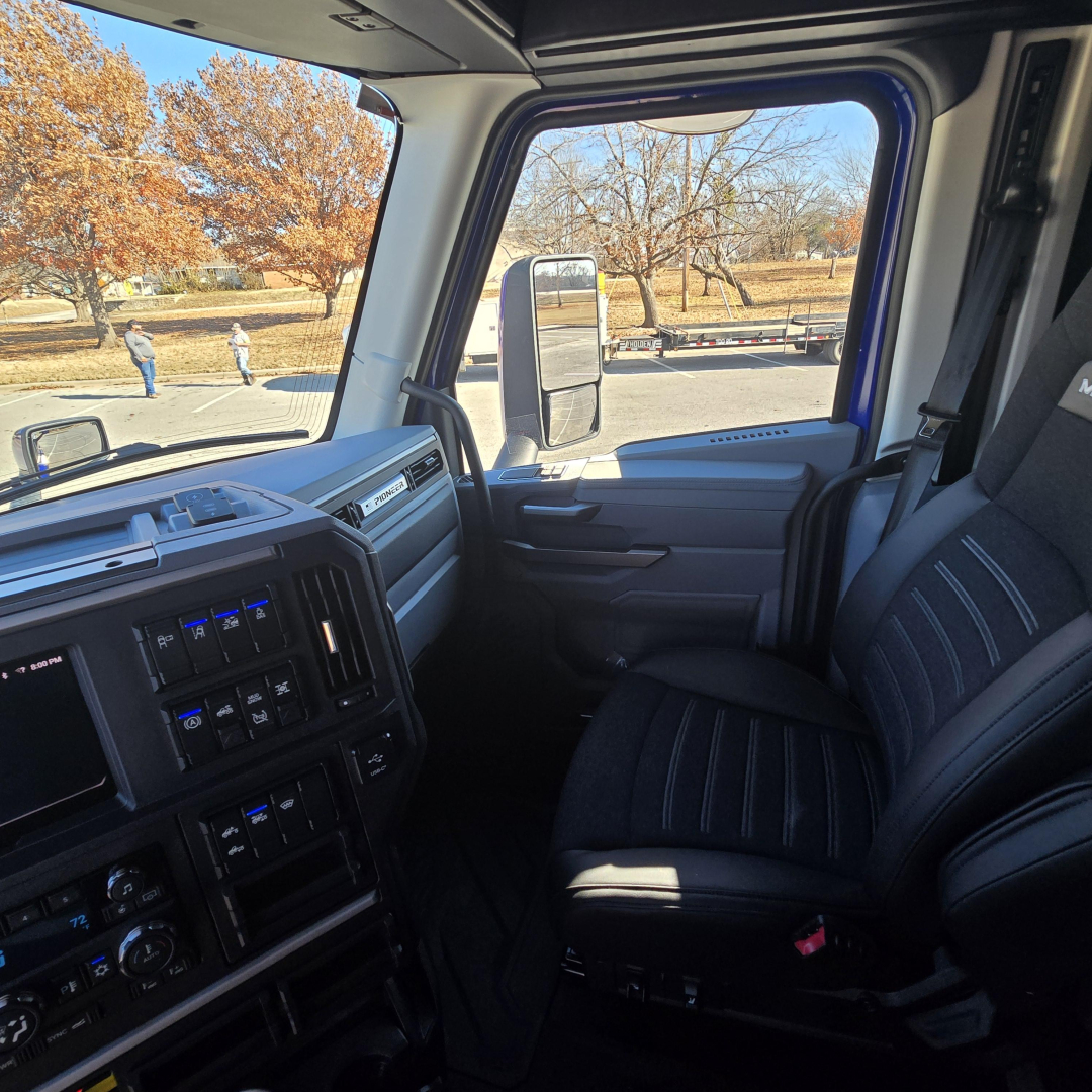 Truck cabin interior view of a 2026 Mack PR64T76H showing driver's seat and dashboard with multiple gauges and controls.