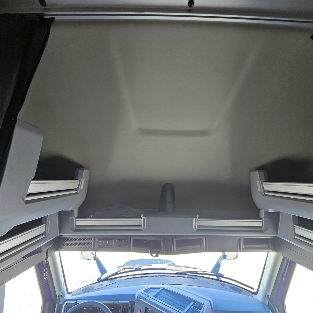 Truck cab interior cargo area with overhead bunk space and dash visible in foreground.