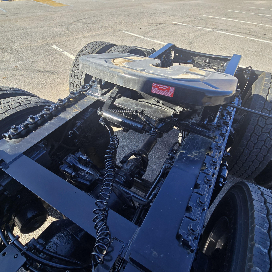 Chassis of a new 2026 Mack PR64T76H truck showing hitch/air lines and fifth wheel, with exposed frame and suspension components.