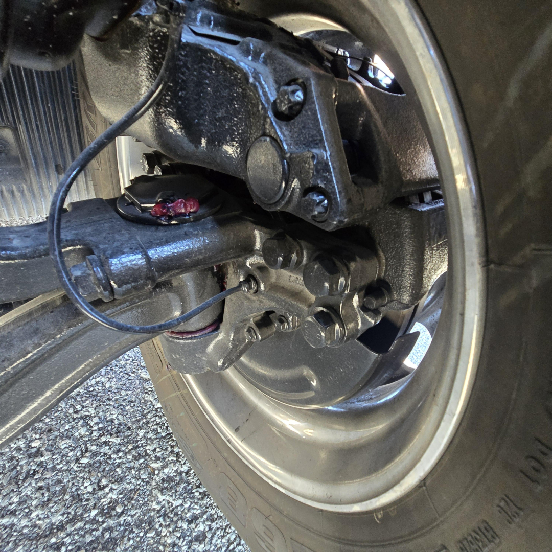 Mack PR64T76H truck drivetrain close-up showing wheel hub and suspension components.