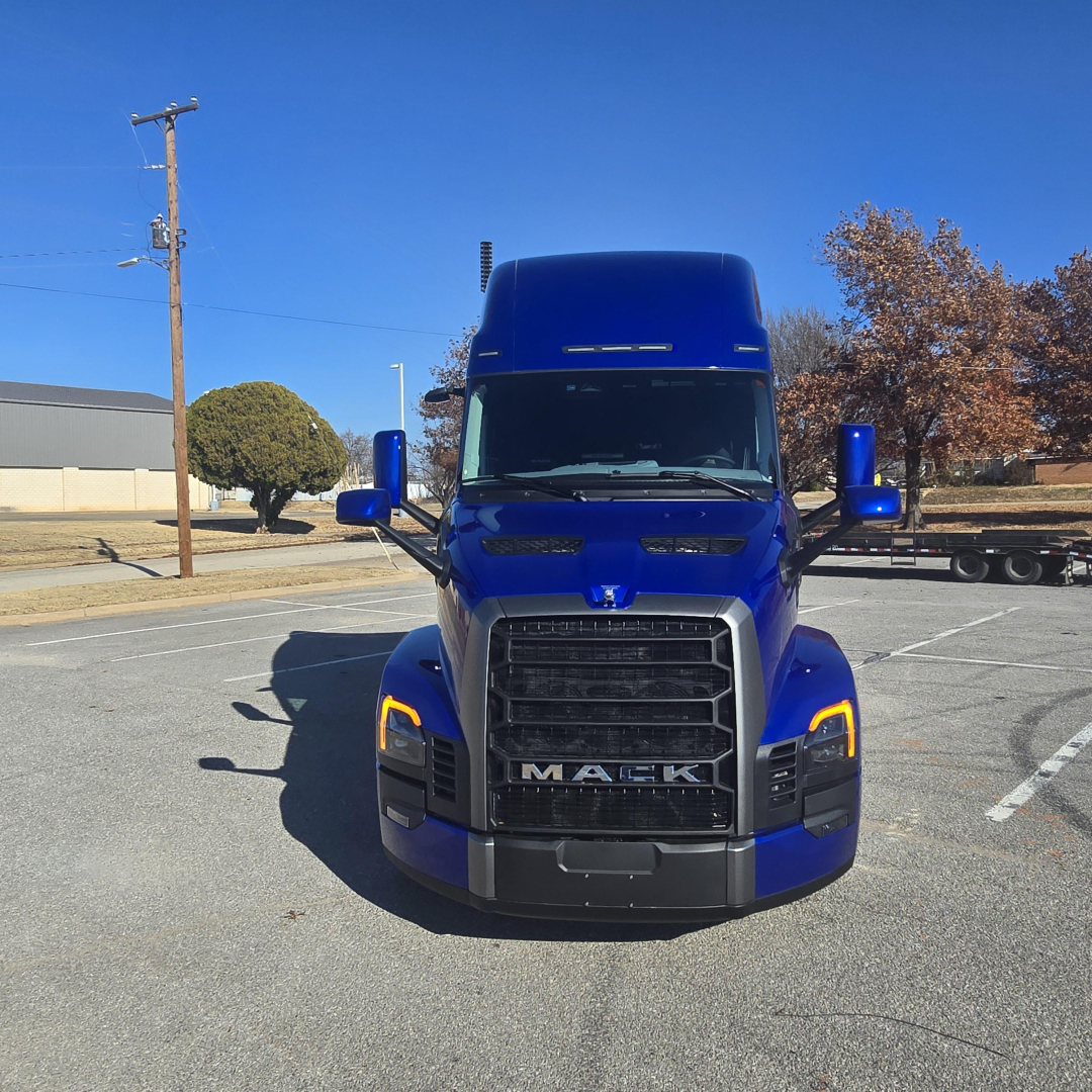 Truck front view showing blue Mack PR64T76H with black grille and yellow turn signals.