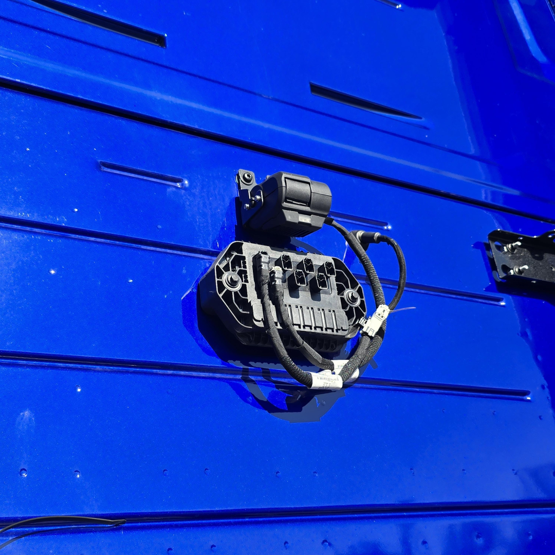 Front view of a Mack PR64T76H sleeper truck showing a power distribution module mounted on a blue exterior panel.