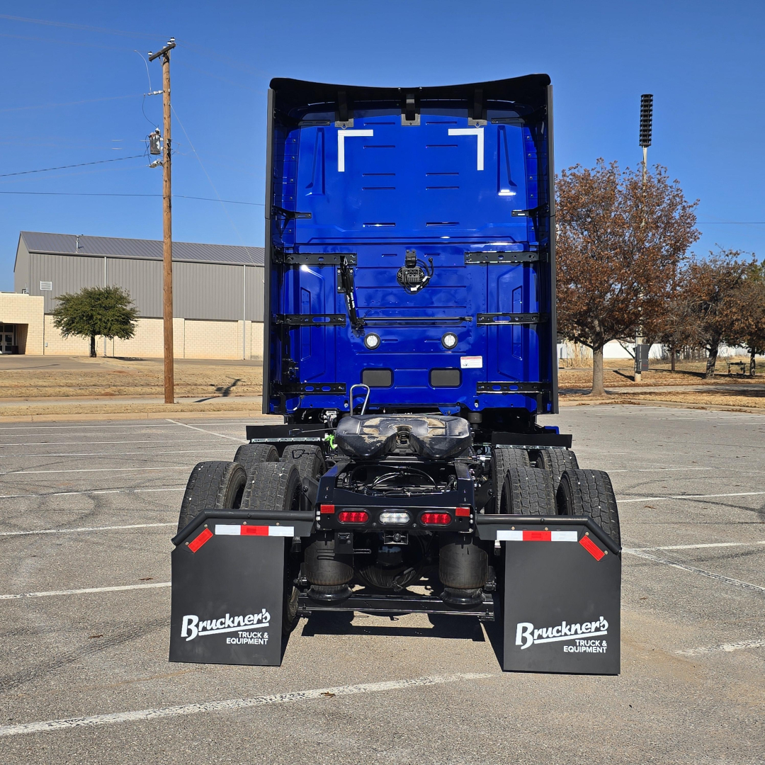 Truck rear view showing blue Mack PR64T76H cab and dual rear axles with black dirt-resistant fenders and mud flaps reading Bruckner's Truck Equipment.