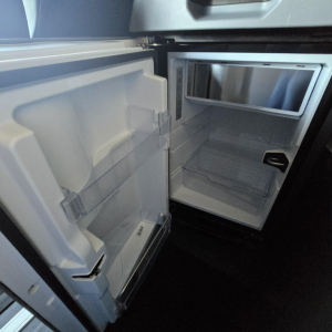 Interior of a new 2026 Mack PR64T76H sleeper cab showing empty refrigerator and open fridge door inside the truck.