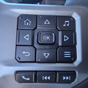 Truck dashboard control pad with navigation buttons and media controls.