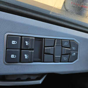 Truck interior switch panel with multiple window and mirror controls on the door, visible on Mack PR64T76H cab interior.