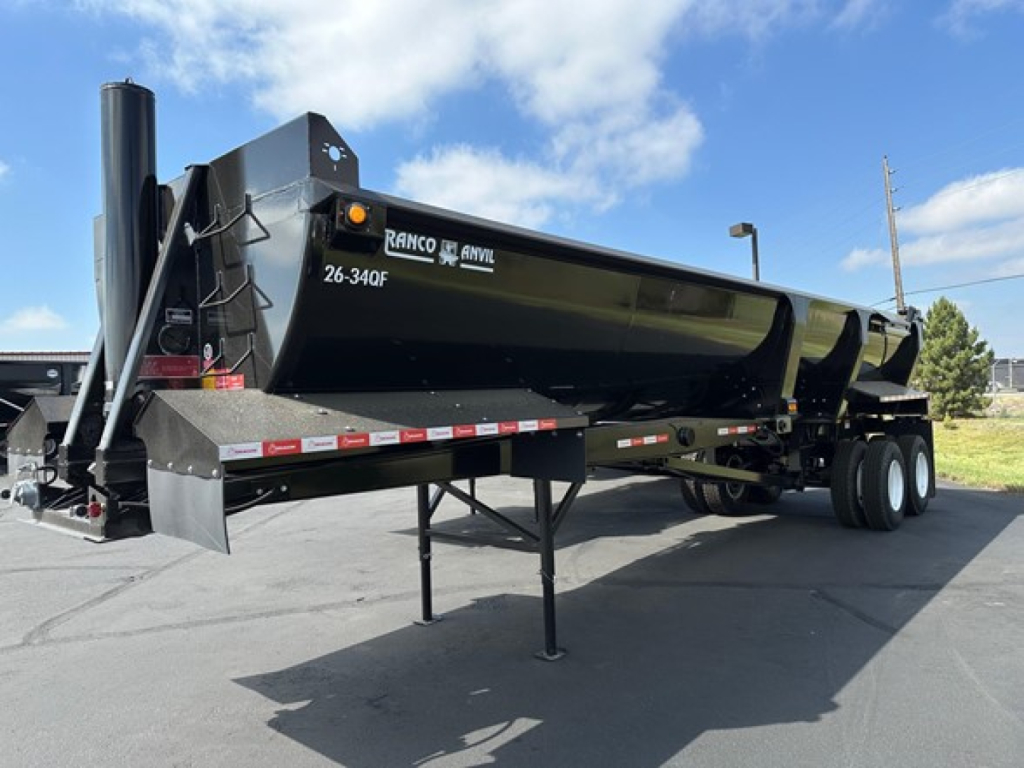 Ranco quarter frame end dump trailer in black with side rails and landing gear visible, 26-34CF model marking on front side, undercarriage with dual rear axles.