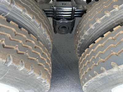 Trailer axle view showing dual rear tires and suspension components between wheels, within a dump trailer chassis.