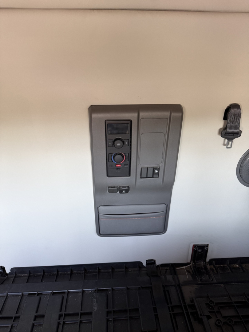 Volvo VNL interior cabinet panel with control switches and storage on wall, view from sleeper area.
