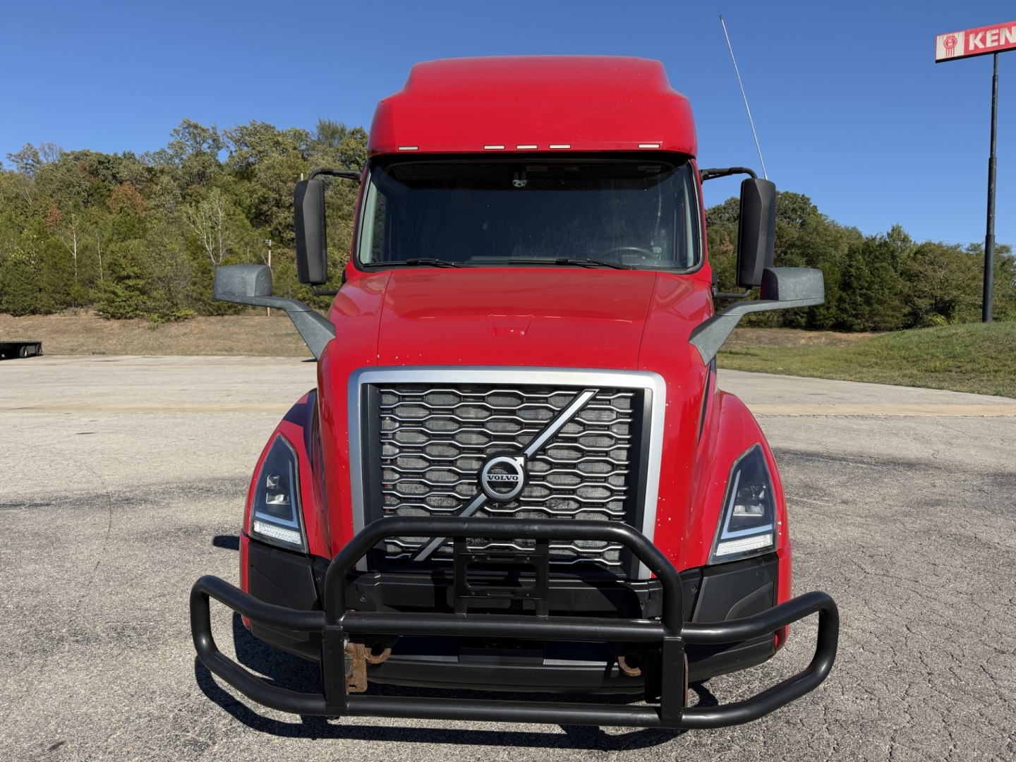 Volvo VNL truck front view showing grille, bumper guard, and red cab with large side mirrors.