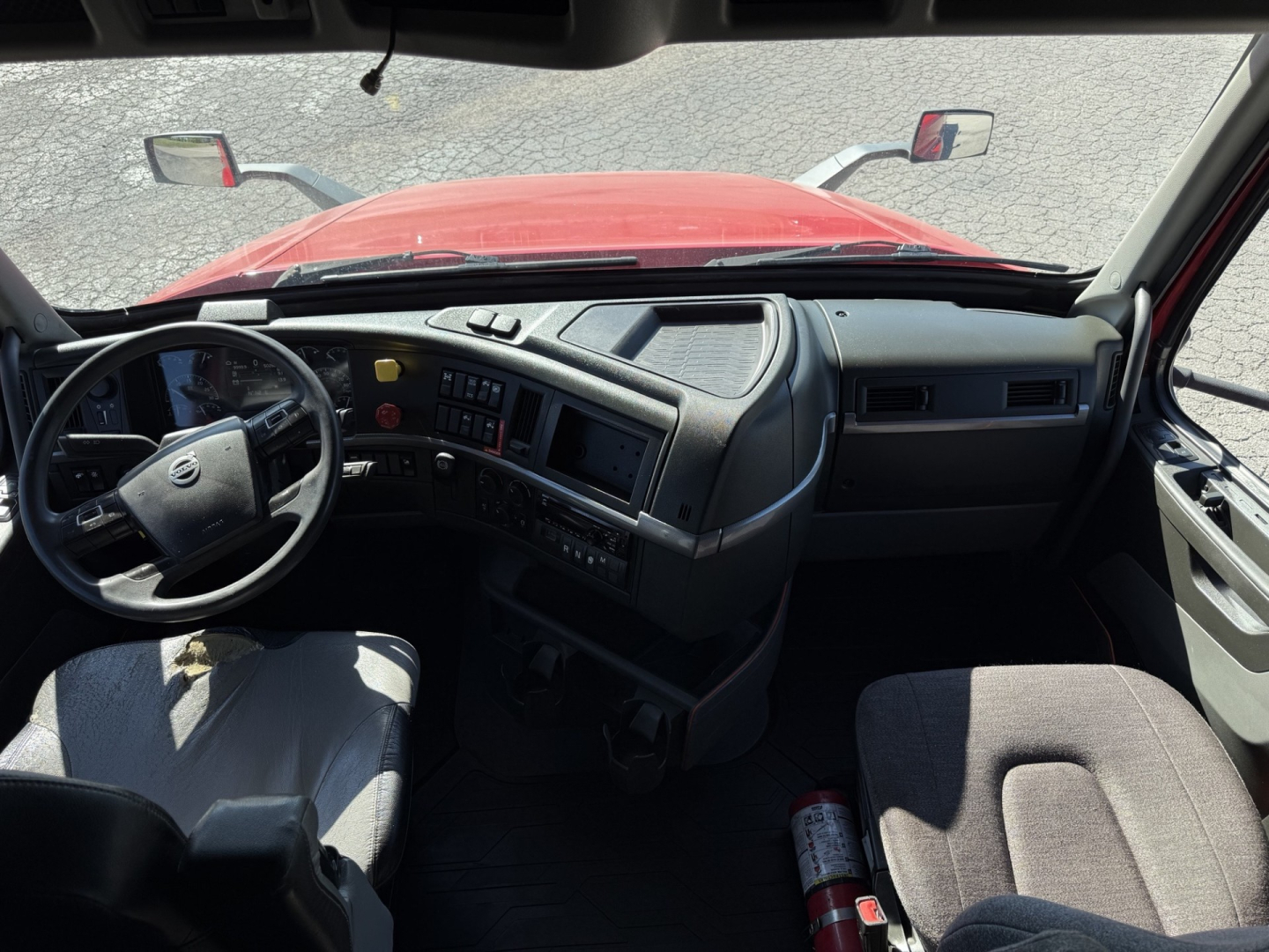 Truck cab interior of a 2021 Volvo VNL64T760 showing dashboard with steering wheel and driver's seat; visible text includes Volvo emblem on wheel and control panels.