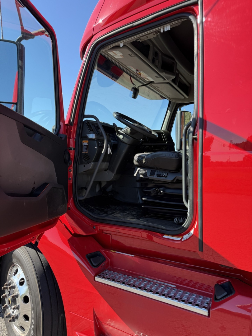 Volvo truck cab interior visible through open door with red exterior and chrome running board.