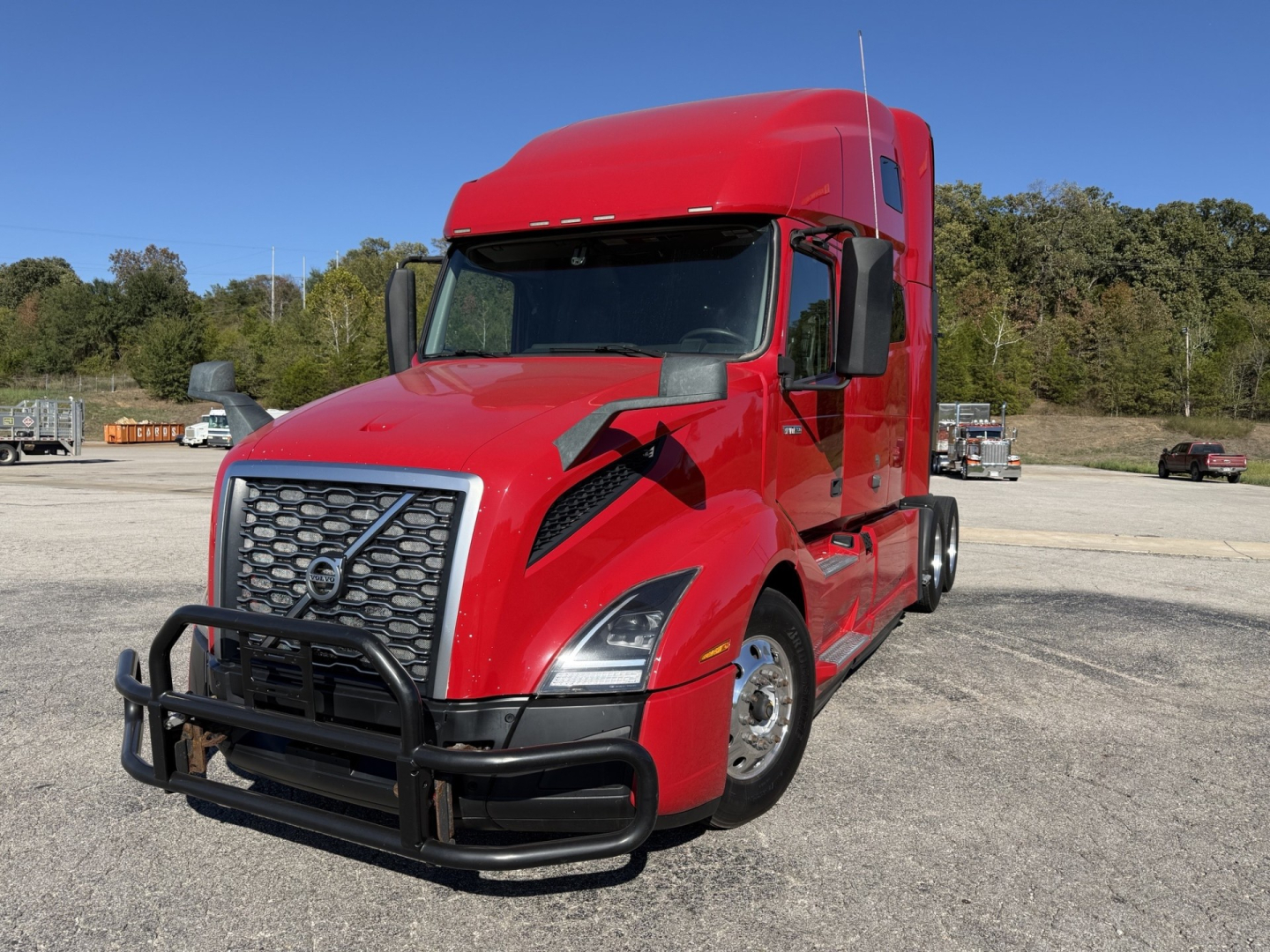 Volvo VNL64T760 truck in red with a front grille guard, day cab sleeper, showing curved hood and high cab, parked outdoors.