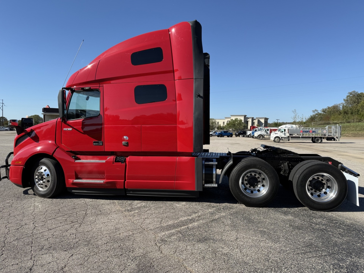 Volvo VNL64T760 truck side view showing red sleeper cab and dual rear axles.