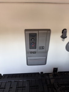 Volvo VNL interior cabinet panel with control switches and storage on wall, view from sleeper area.