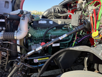 Volvo VNL64T760 engine bay showing green engine block, turbocharger pipe, hoses, and various colored electrical wires in a truck.