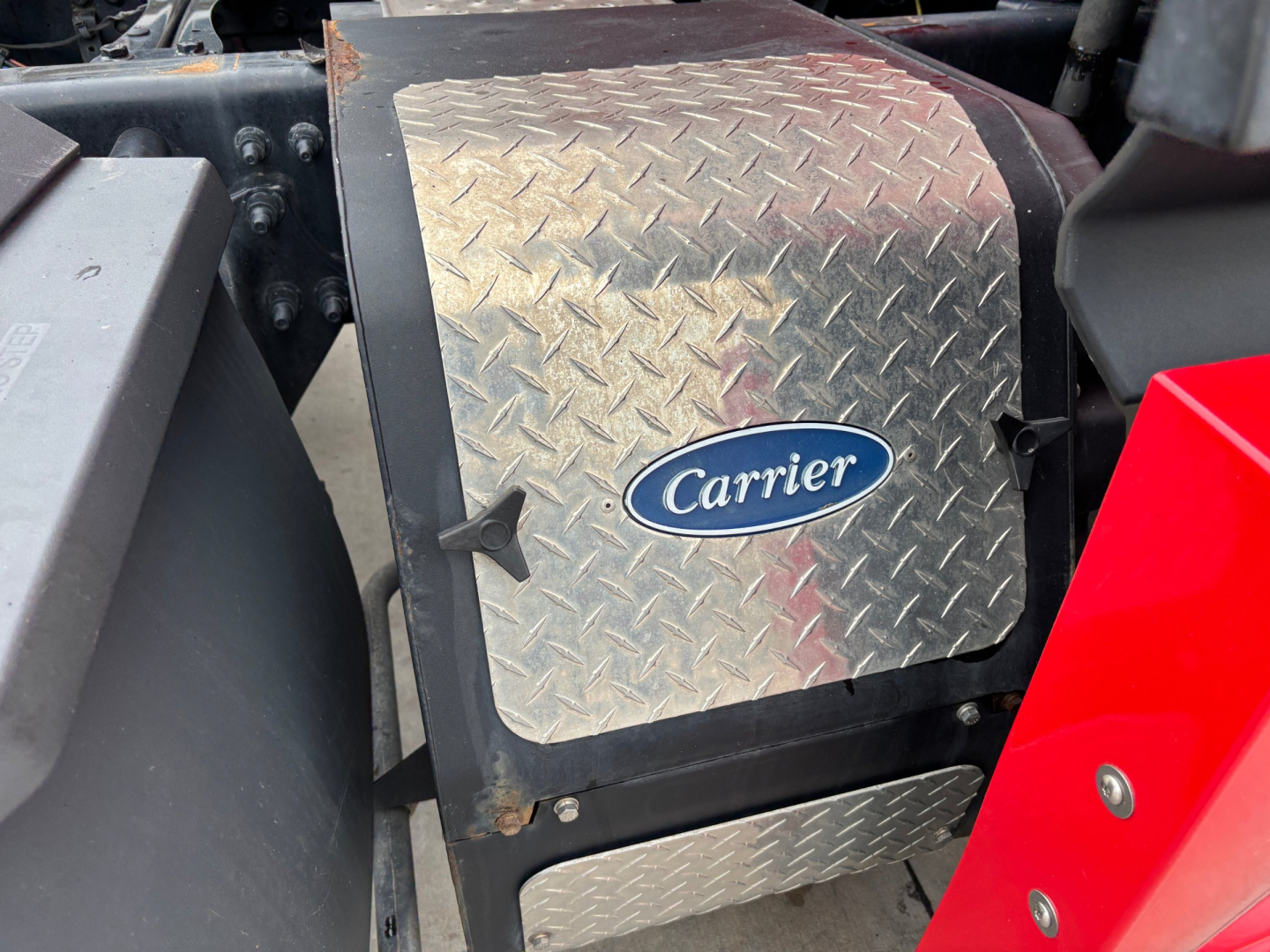 Carrier auxiliary fuel tank/box with diamond-plate cover on Freightliner PT126064ST showing metal steps and red body panel.