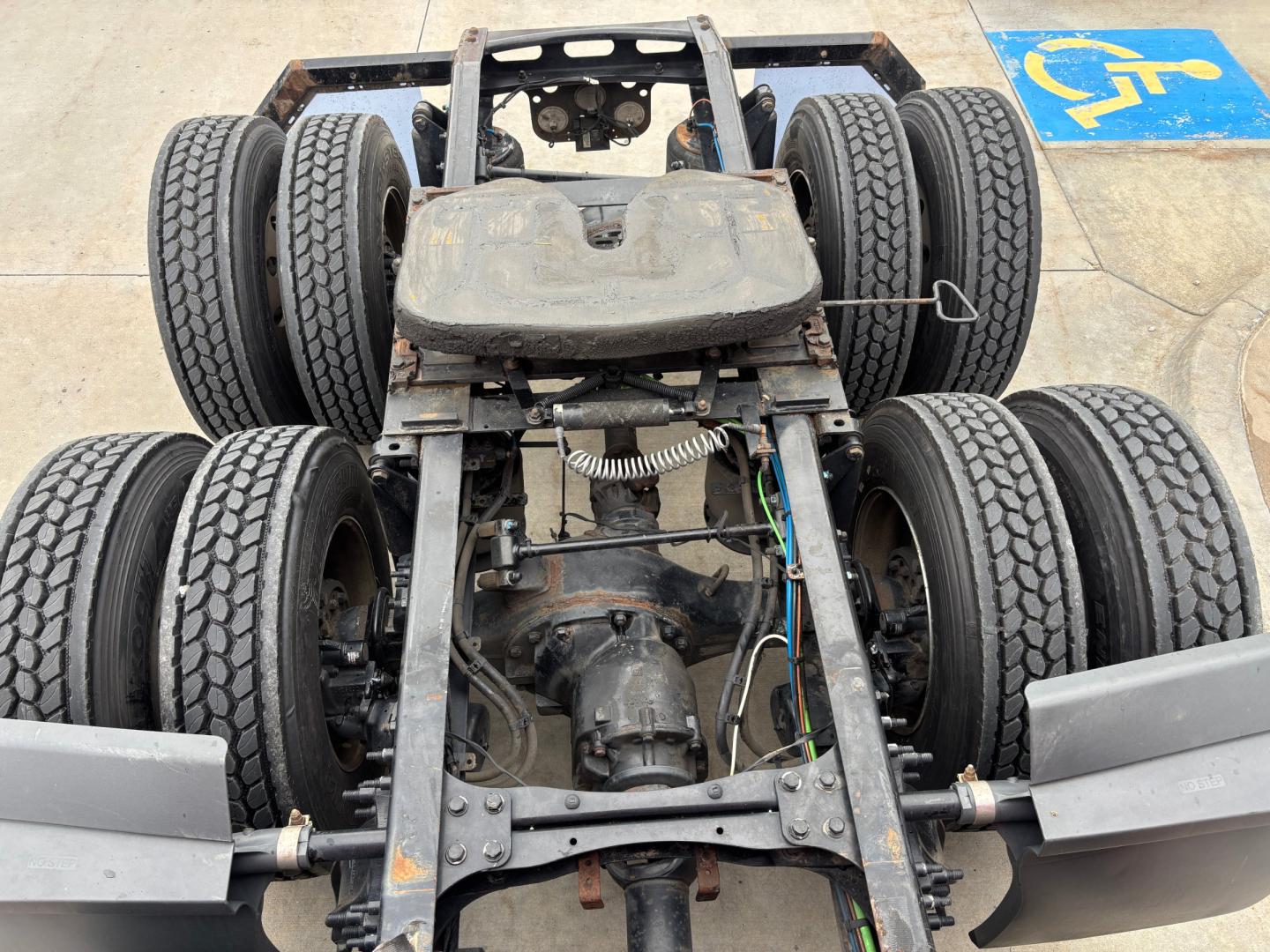 Freightliner PT126064ST truck chassis showing dual rear axles and drivetrain components with tires, frame rails, and suspension visible.