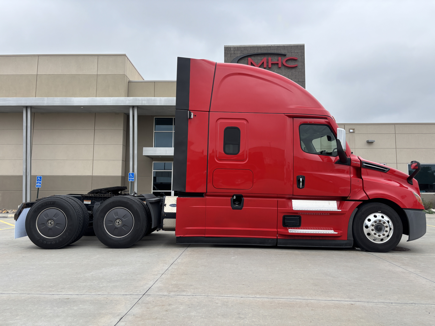 Truck side view showing a red Freightliner cab with sleeper, black chassis and wheels, no visible damage.