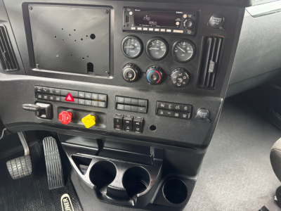 Dashboard of Freightliner PT126064ST sleeper truck showing instrument cluster, climate controls, radio, and switch panel with cup holders and storage compartments.