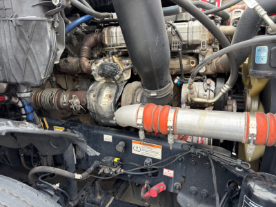 Engine bay of Freightliner PT126064ST showing engine components, belts, hoses, and a red-and-white exhaust/piping section.