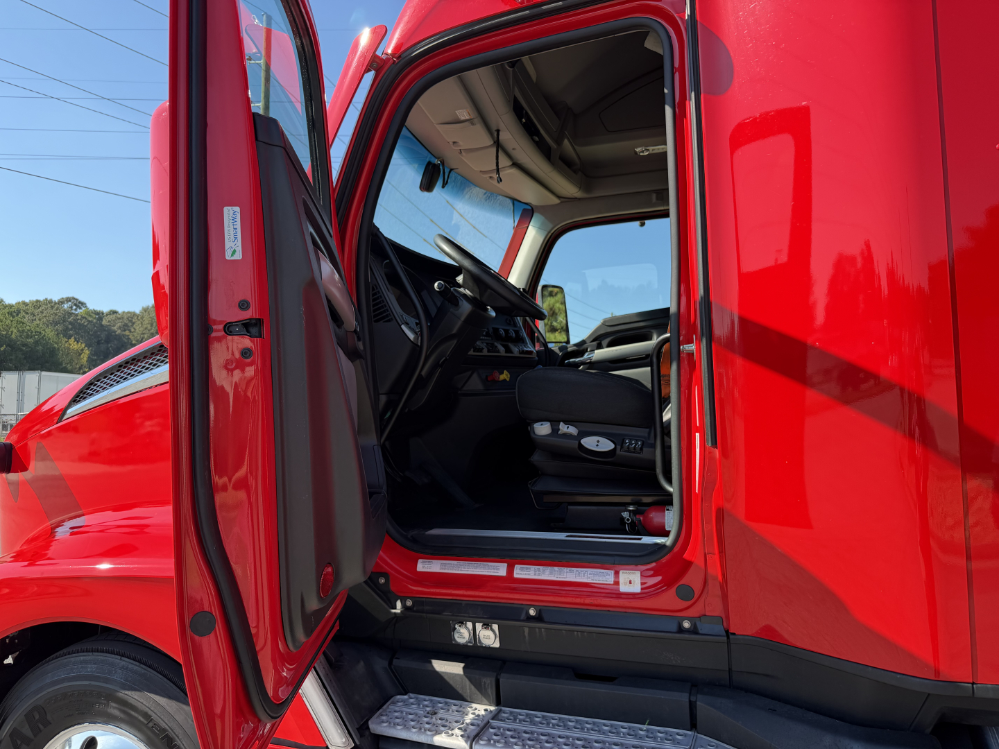 Kenworth T680 truck cab interior view through open door showing driver seat and controls.