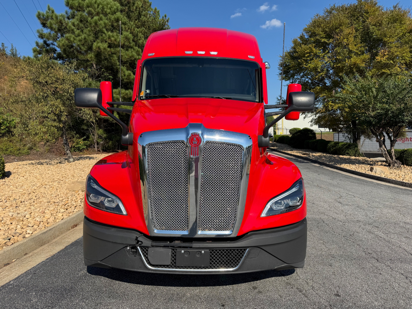 Kenworth T680 front view showing bold chrome grille and red cab with black bumper