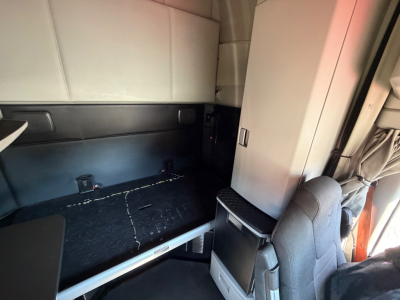 Kenworth interior sleeper cab cargo area showing side storage cabinet and seating area with light-colored upholstery
