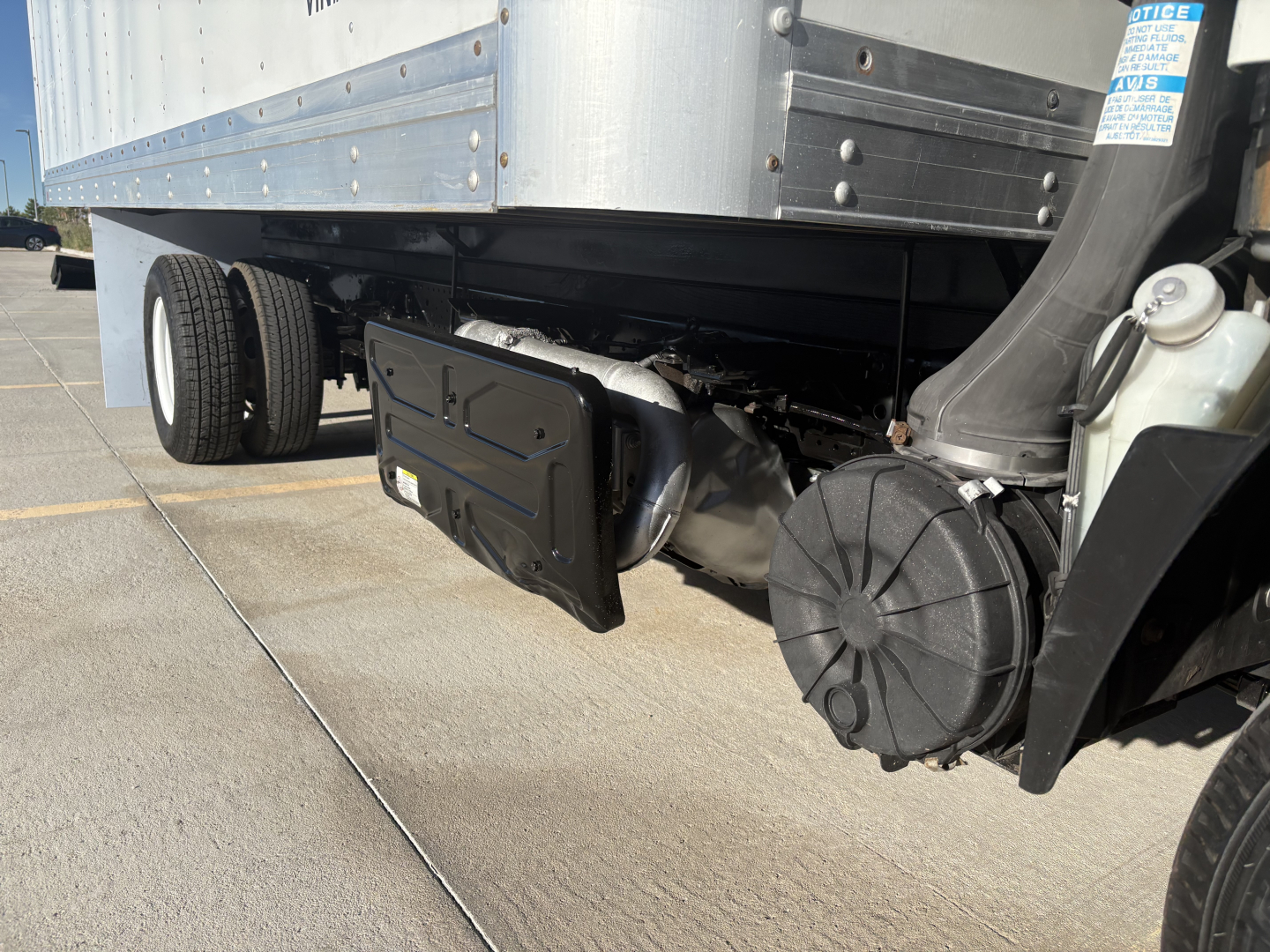 Isuzu NPR undercarriage showing rear differential, driveshaft, suspension, and fuel tank near box truck bed.