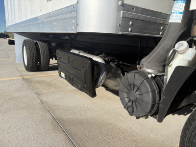 Isuzu NPR undercarriage showing rear differential, driveshaft, suspension, and fuel tank near box truck bed.