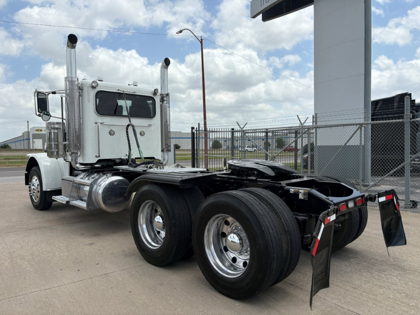 Peterbilt 389 conventional daycab tractor chassis and rear dual wheels, chrome exhaust stacks, aluminum fuel tanks, rear underride guards visible.