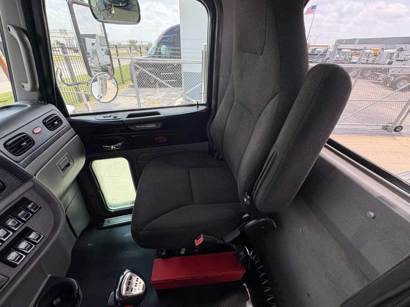 Peterbilt 389 truck cab interior showing driver seat and dashboard, with gear shifter on floor and controls on panel.