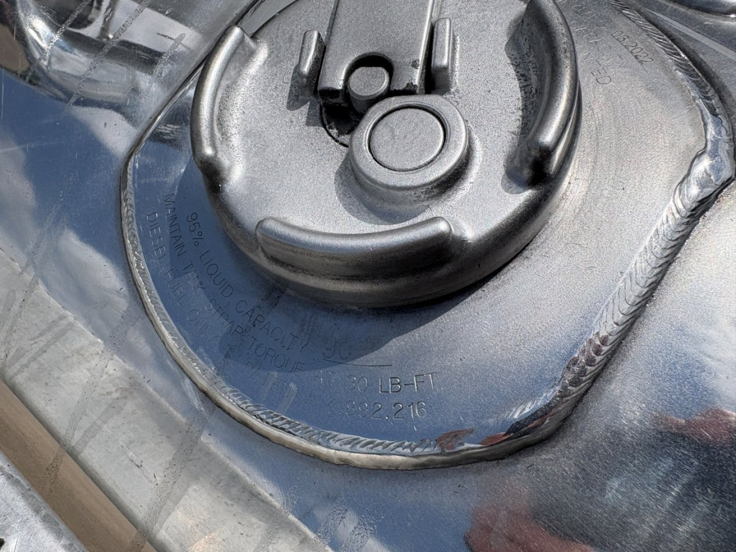 Peterbilt 389 fuel tank cap area showing circular fuel cap and surrounding metal surface with embossed text.