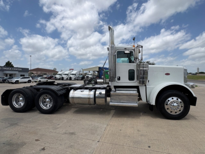 Peterbilt 389 daycab in white with chrome exhaust stacks and fuel tanks, side view showing cab, dual rear axles, and long wheelbase.