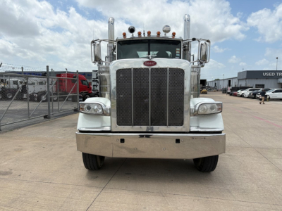 Peterbilt 389 front view showing large black grille, chrome bumper, dual round headlights, and Peterbilt emblem; chrome mirrors and cab details visible.