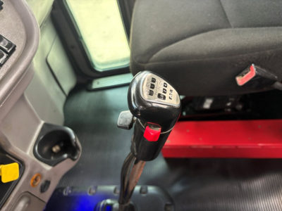 Gear shift knob with numeric keypad and surrounding interior of a Peterbilt truck cab. Visible details include the shifter with buttons and a portion of the driver seat and dashboard.