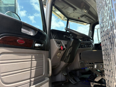 Peterbilt 389 truck interior view of cab door and dashboard with steering wheel and pedals visible.