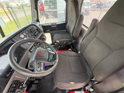 Peterbilt 389 cab interior with steering wheel, dashboard gauges, and two driver's seats; VIN tag not visible; diesel truck cabin.