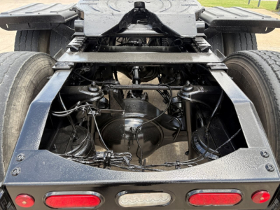 Peterbilt 389 truck rear chassis view showing drive axle, suspension, and wiring harnesses; rear bumper with taillights visible.