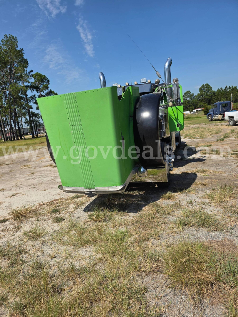 Truck engine bay component with a large green radiator housing and exhaust stacks visible from rear-side angle.