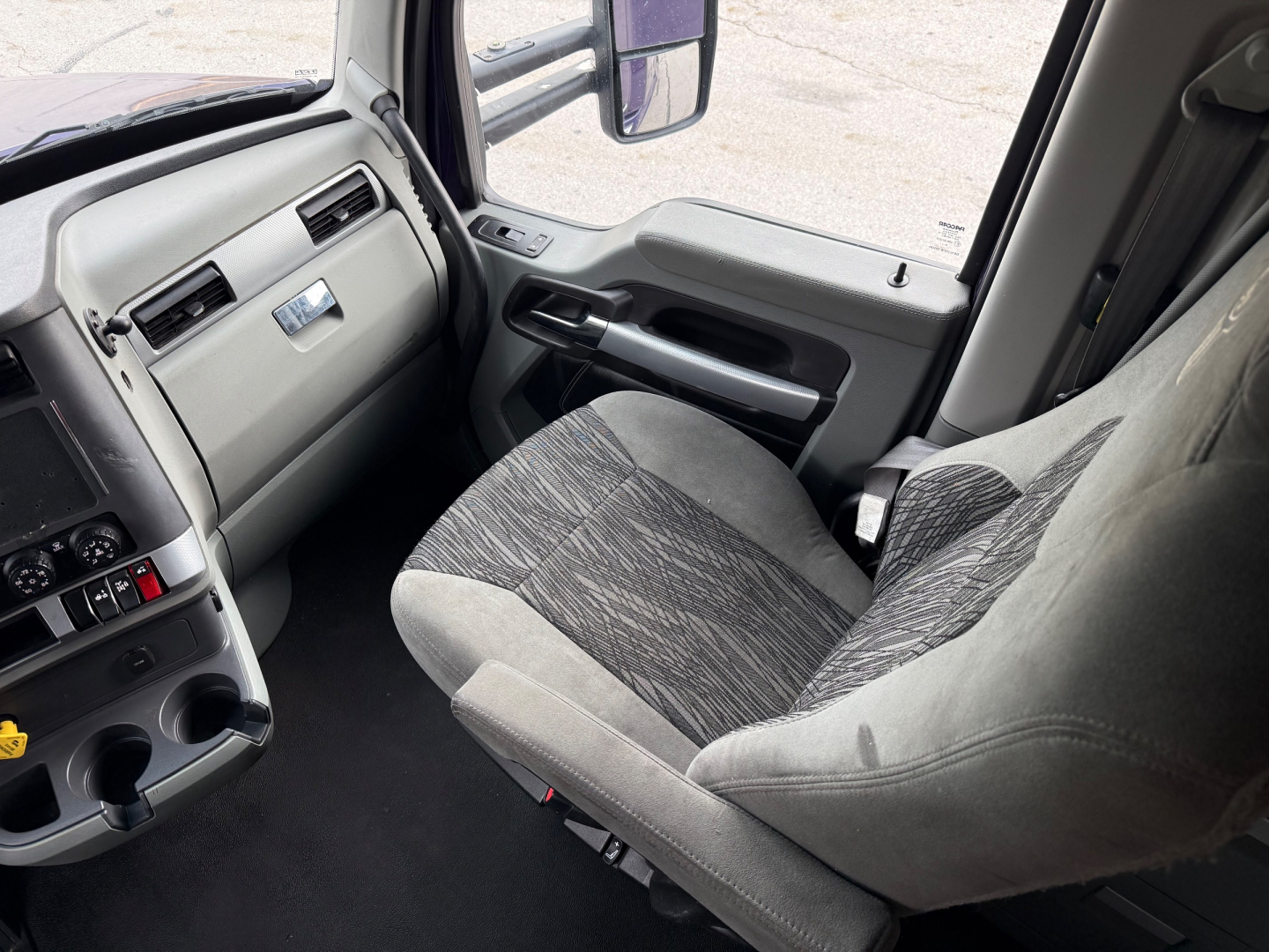 Kenworth T680 cabin interior showing driver seat and dashboard with gray upholstery and control panel