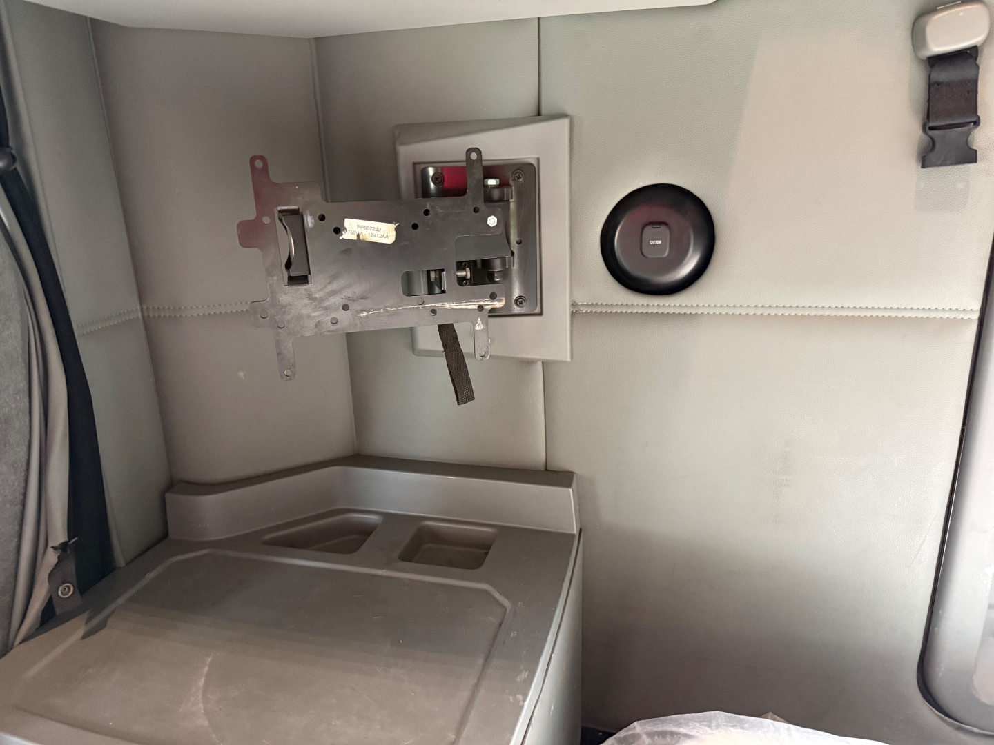 Kenworth T680 sleeper cab interior showing instrument panel mounting bracket and circular fuel cap port on light gray panel.