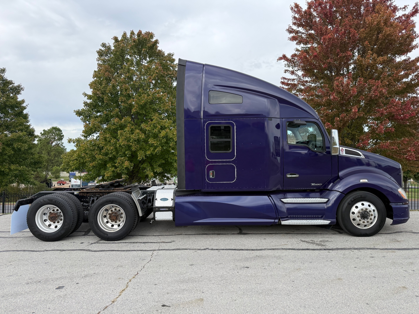 Kenworth T680 semi-truck side view showing purple/satin paint, sleeper cab, dual rear axles, and chrome fuel tanks.