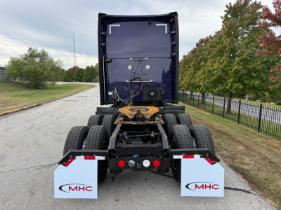 Kenworth T680 rear view showing fifth wheel, dual rear axles, mud flaps with MHC logos, and drivetrain area.