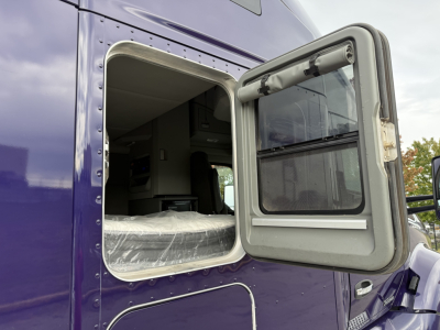 Kenworth T680 side view showing an open sleeper cab window and exterior purple paint