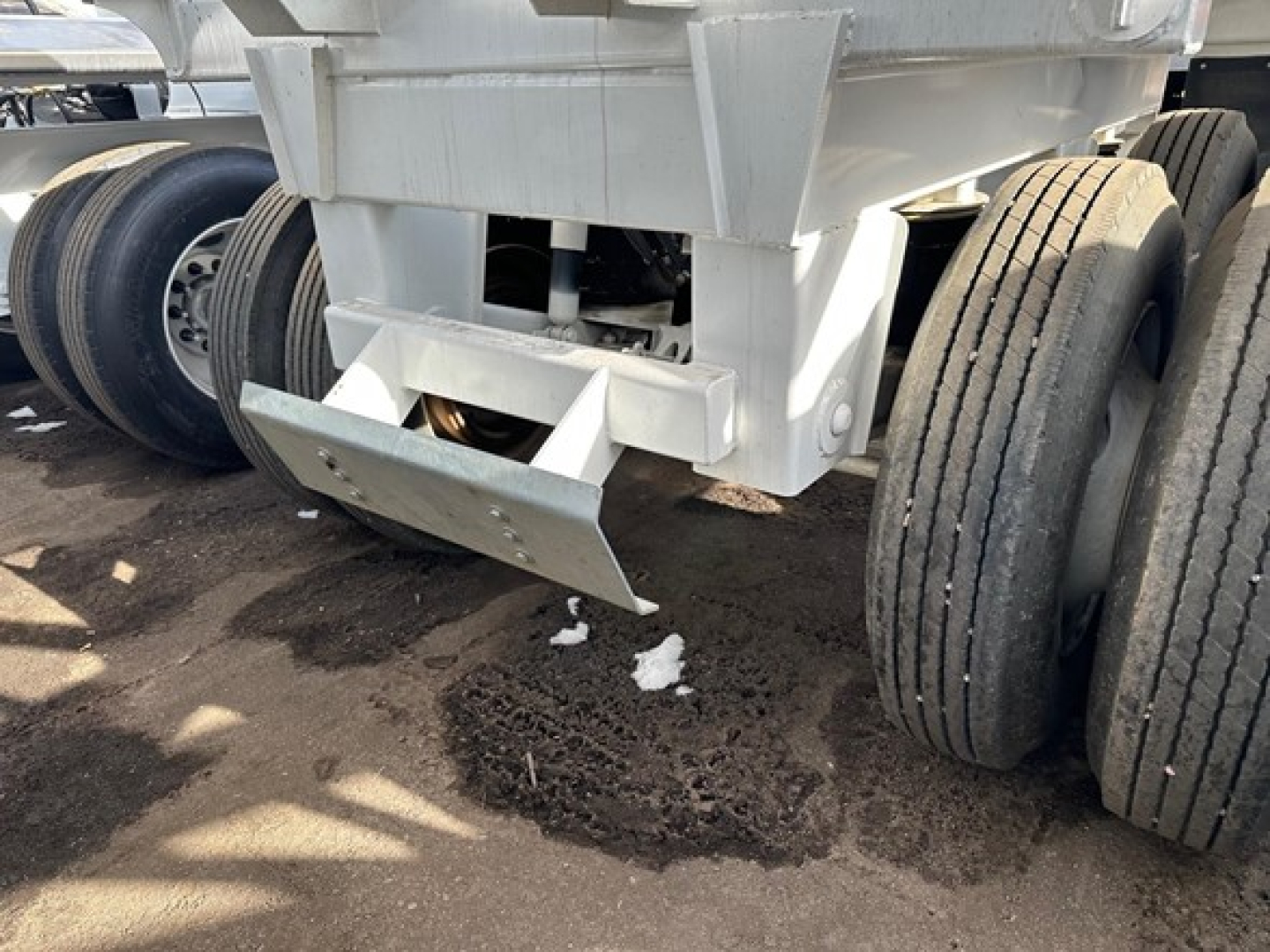 Bottom dump trailer rear view showing twin axle wheels and underside hitch area with lifting mechanism and tailgate.